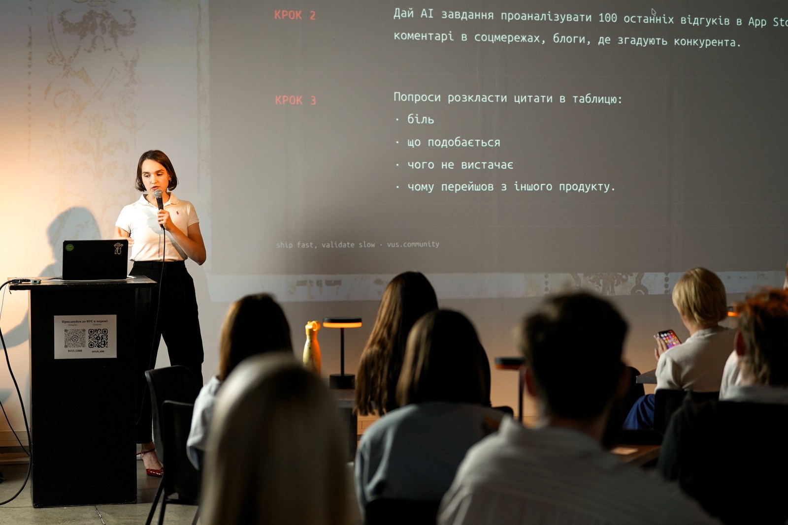 Kraków Tech Mixer #2: Ship It, 3 вересня 2026 року, HEVRE. Фото: ВУС. Спікерка з мікрофоном презентує слайд із кроками, а зал уважно слухає на Kraków Tech Mixer #2